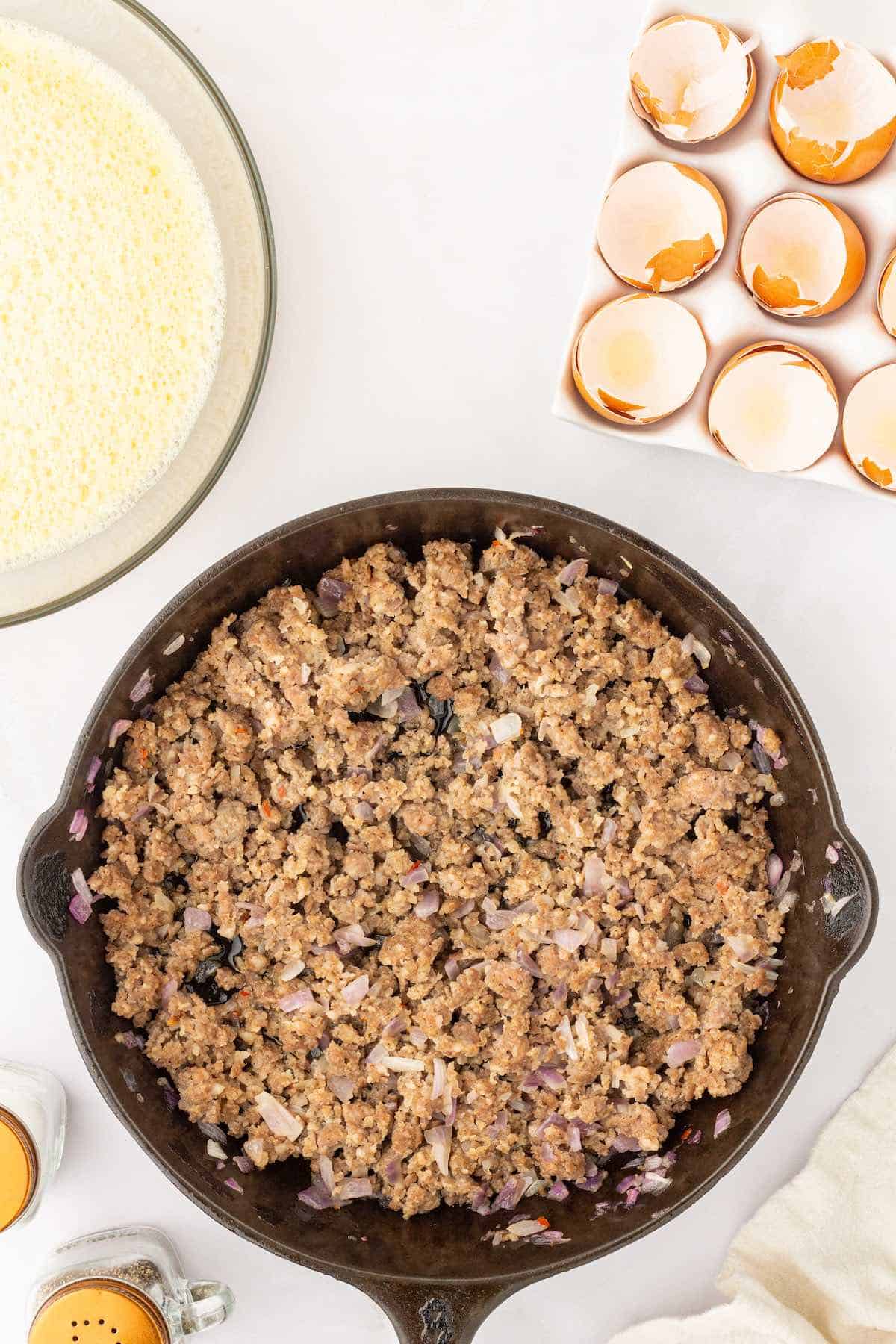 Browned breakfast sausage and onions in a cast iron pan.