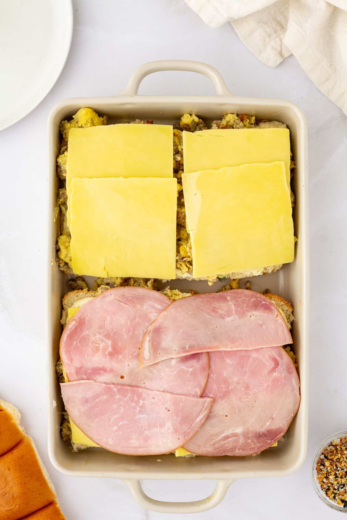 Ham and cheese on top of dinner rolls and scrambled eggs.