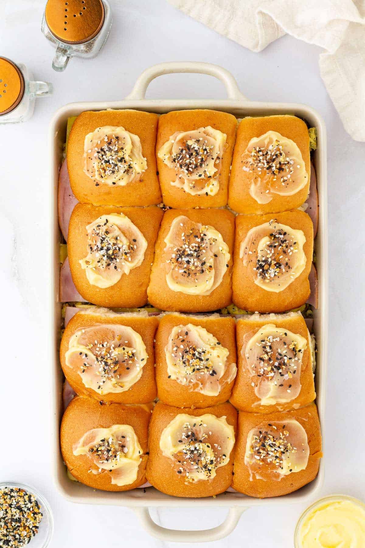 Honey butter topped hawaiian rolls in a casserole dish.