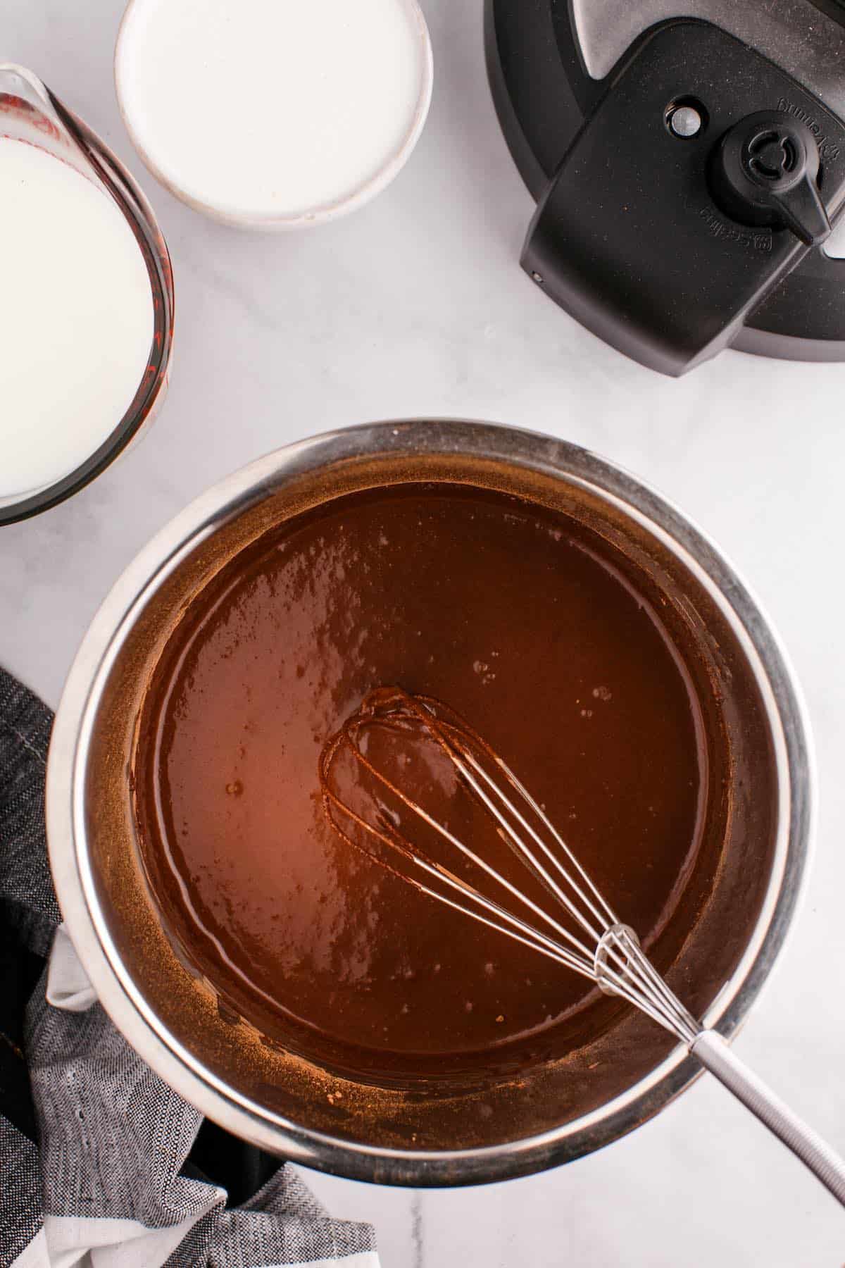 A dark chocolate liquid in an instant pot with a whisk.