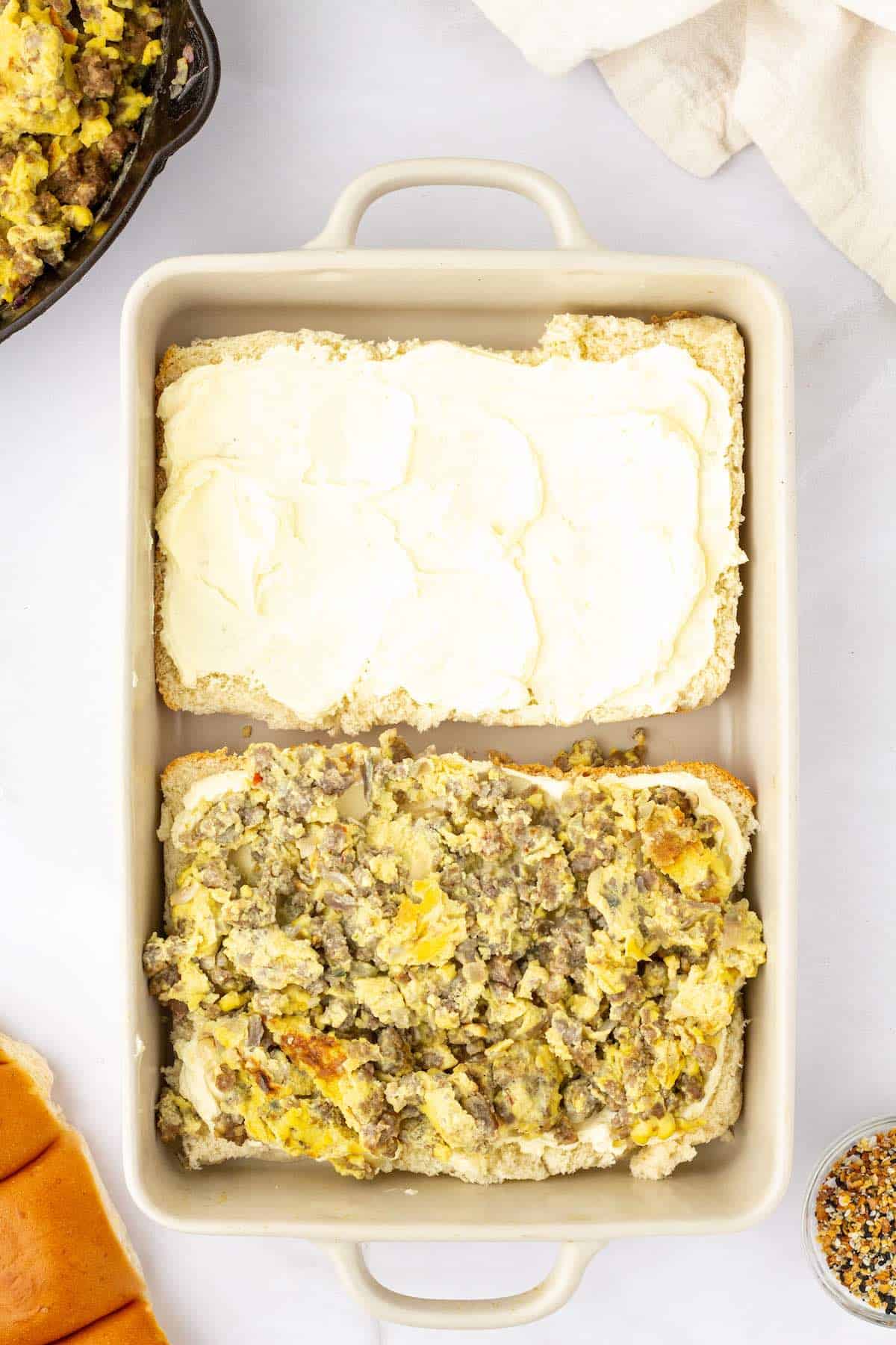 Slider buns topped with cream cheese and scrambled eggs and sausage.