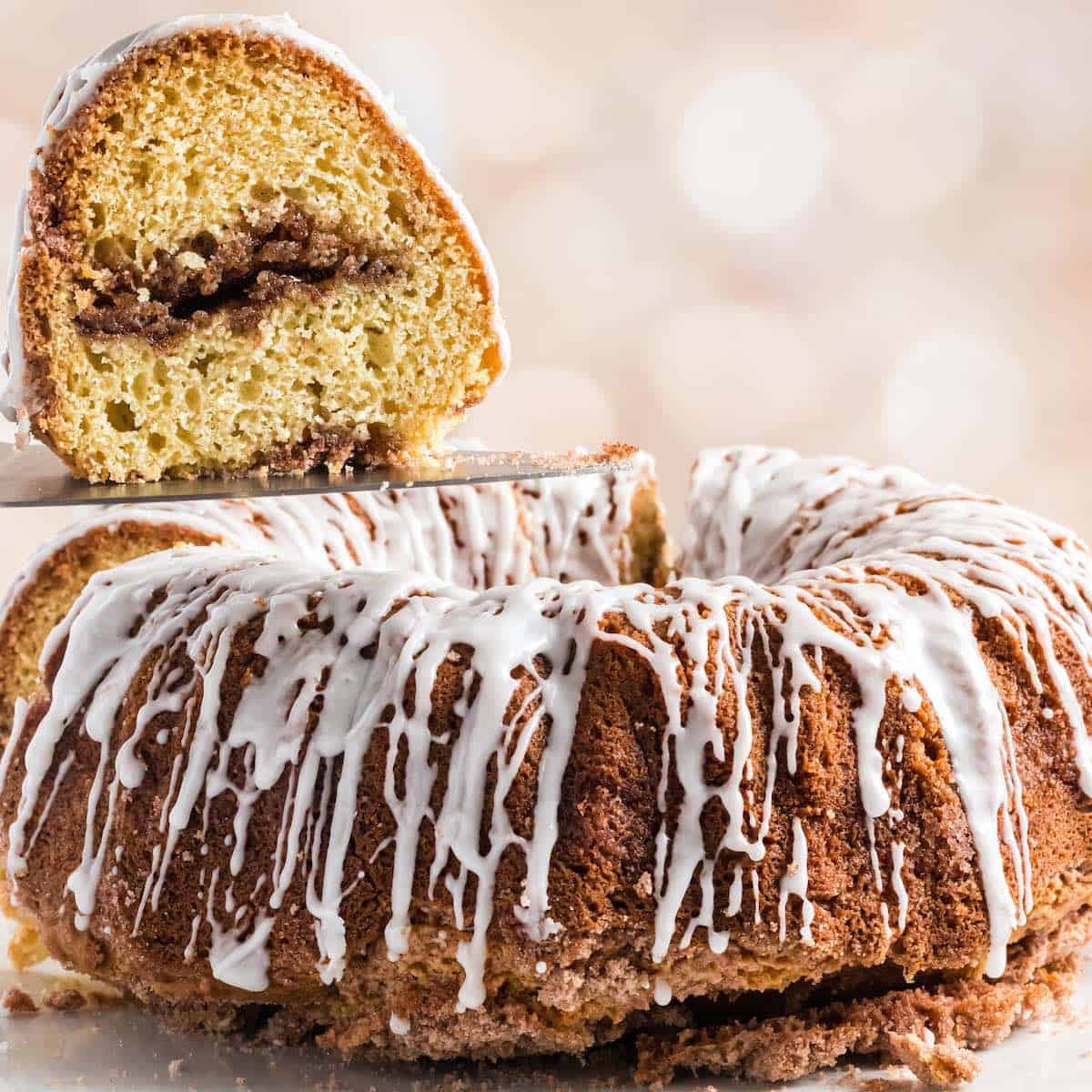 A cinnamon streusel filled sour cream coffee cake with glaze drizzled.