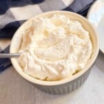 A bowl of whipped cream with a spoon in it.