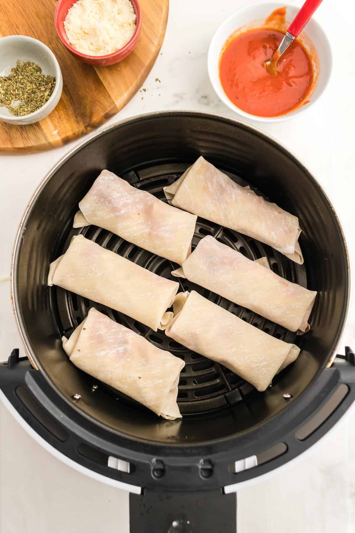 An air fryer basket filled with six pizza eggrolls.