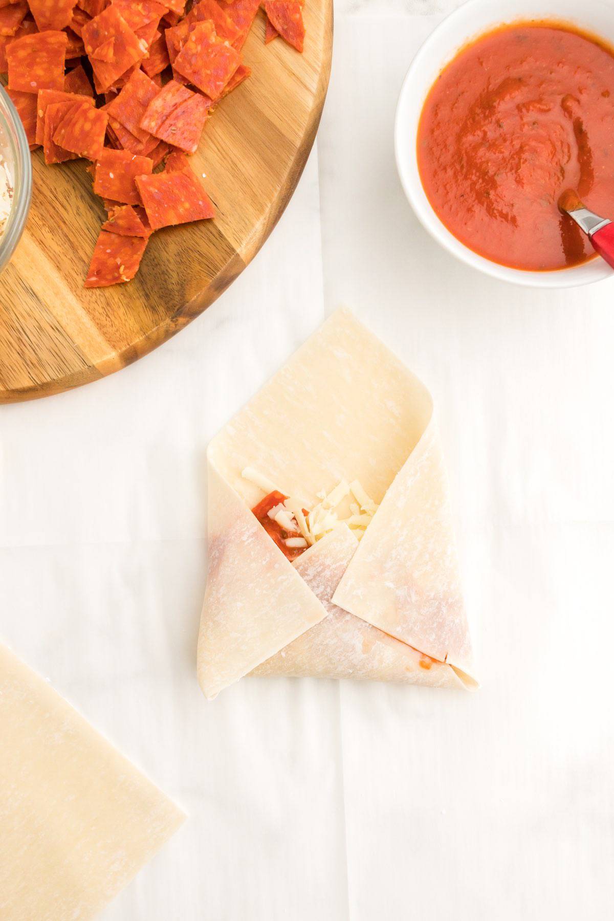 A partially folded egg roll with three sides enclosed.