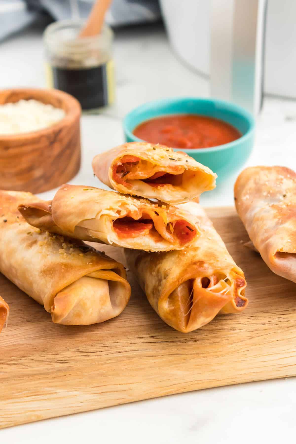 Cut open pizza egg rolls showing sauce, cheese and pepperoni.