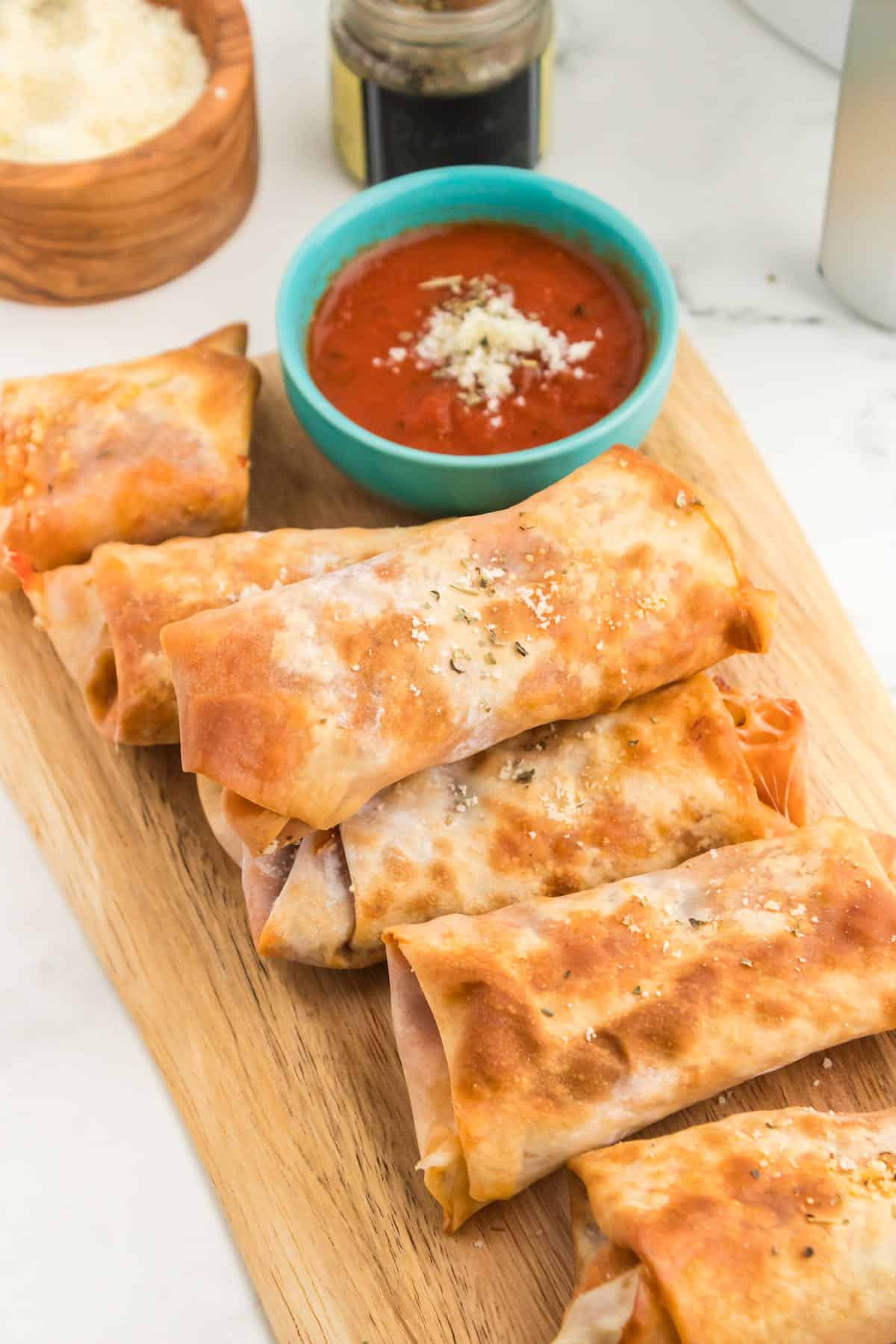 A tray of cooked golden brown pizza egg rolls.