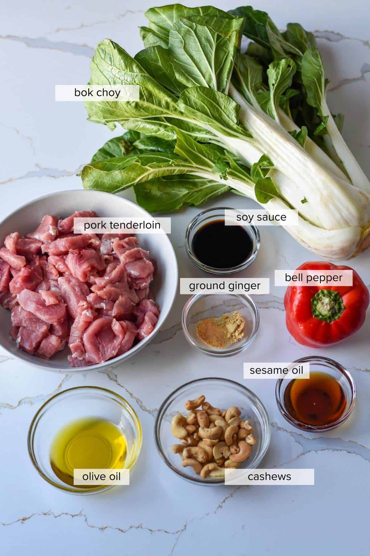 Ingredients including pork tenderloin, bok choy, red bell pepper, soy sauce, sesame oil, cashews, ground ginger and olive oil.