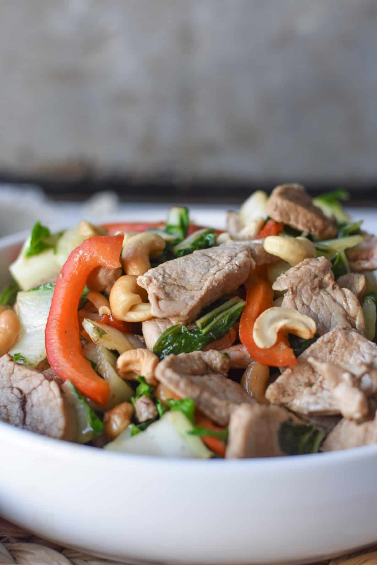 A bowl of keto pork stir fry with veggies and cashews.
