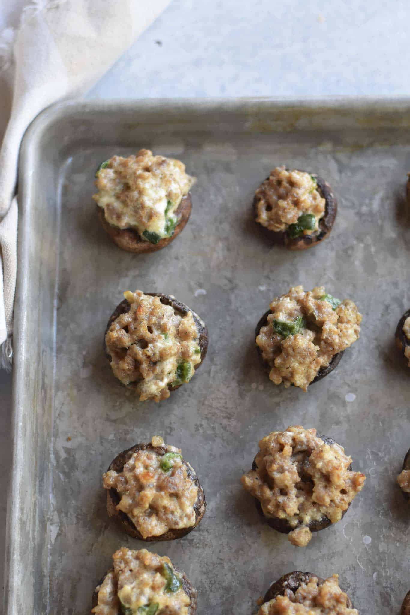 Stuffed mushrooms and sausage on a pan.