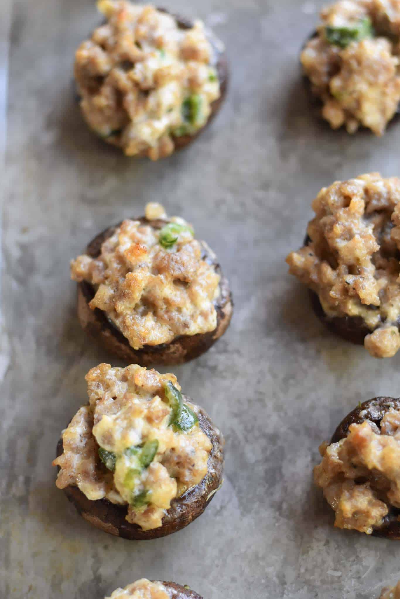 Lightly browned sausage stuffed mushrooms on a sheet pan.