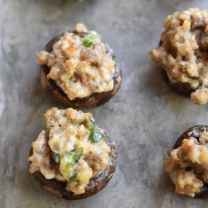 Sausage stuffed mushrooms with cream cheese on a sheet pan.