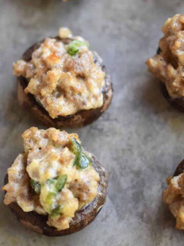 Sausage stuffed mushrooms with cream cheese on a sheet pan.