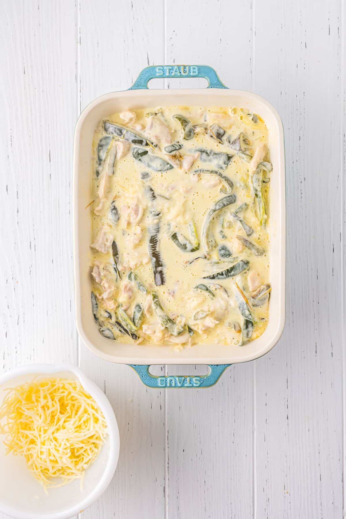 An unbaked casserole with poblano peppers and a creamy sauce.