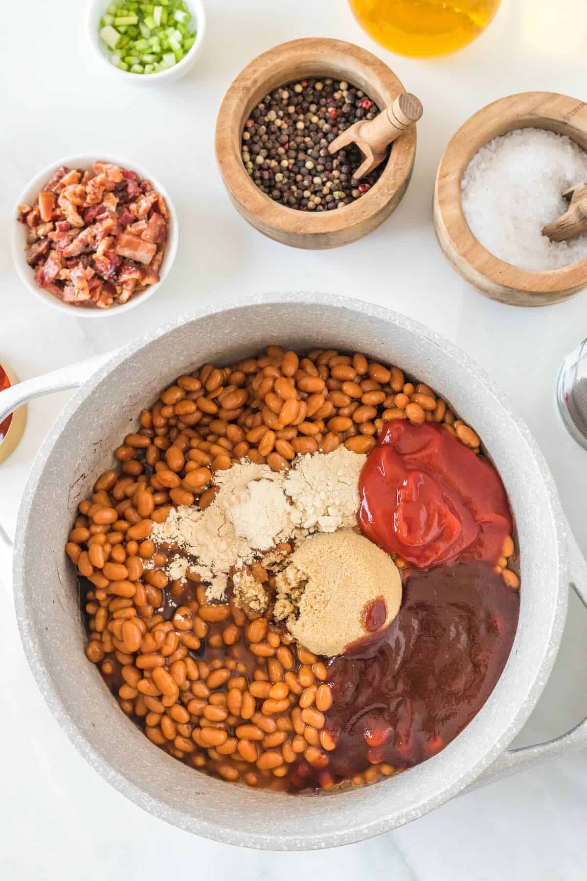 Baked beans in a large pot with ketchup, brown sugar, bbq sauce and spices.