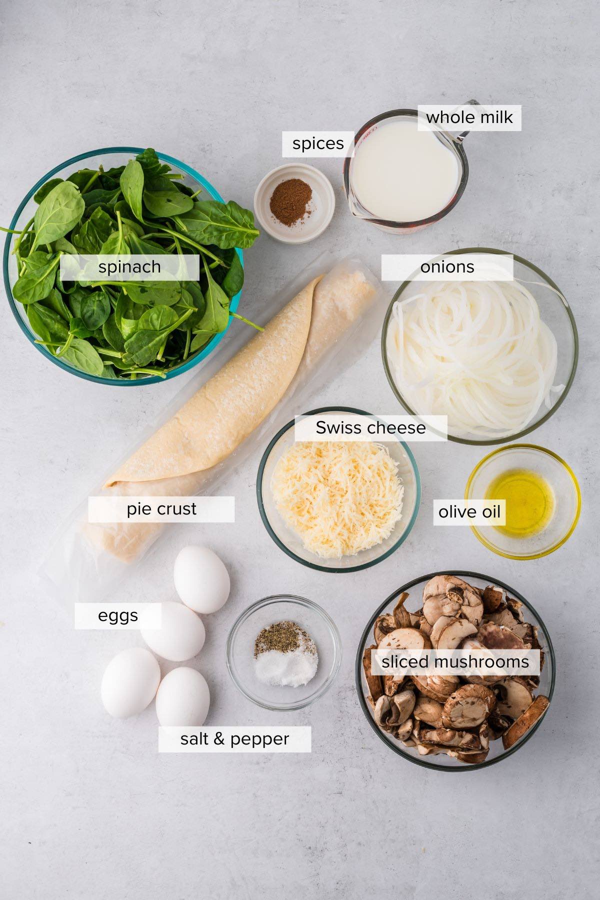 Mushroom spinach quiche ingredients on a kitchen table.