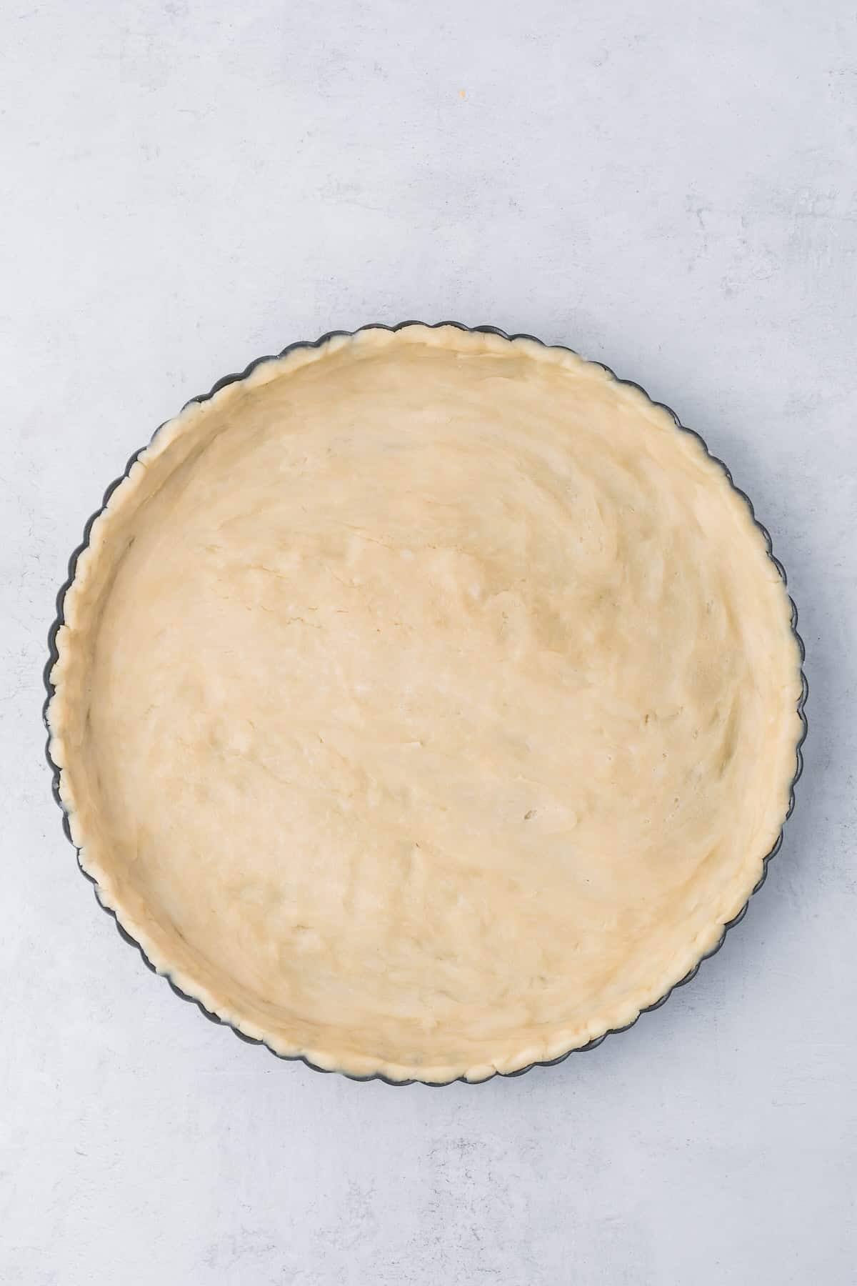 Uncooked pie crust in a tart pan.