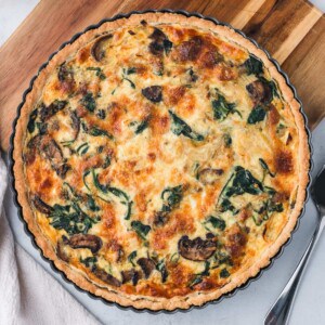 A mushroom and spinach quiche in a tart pan.