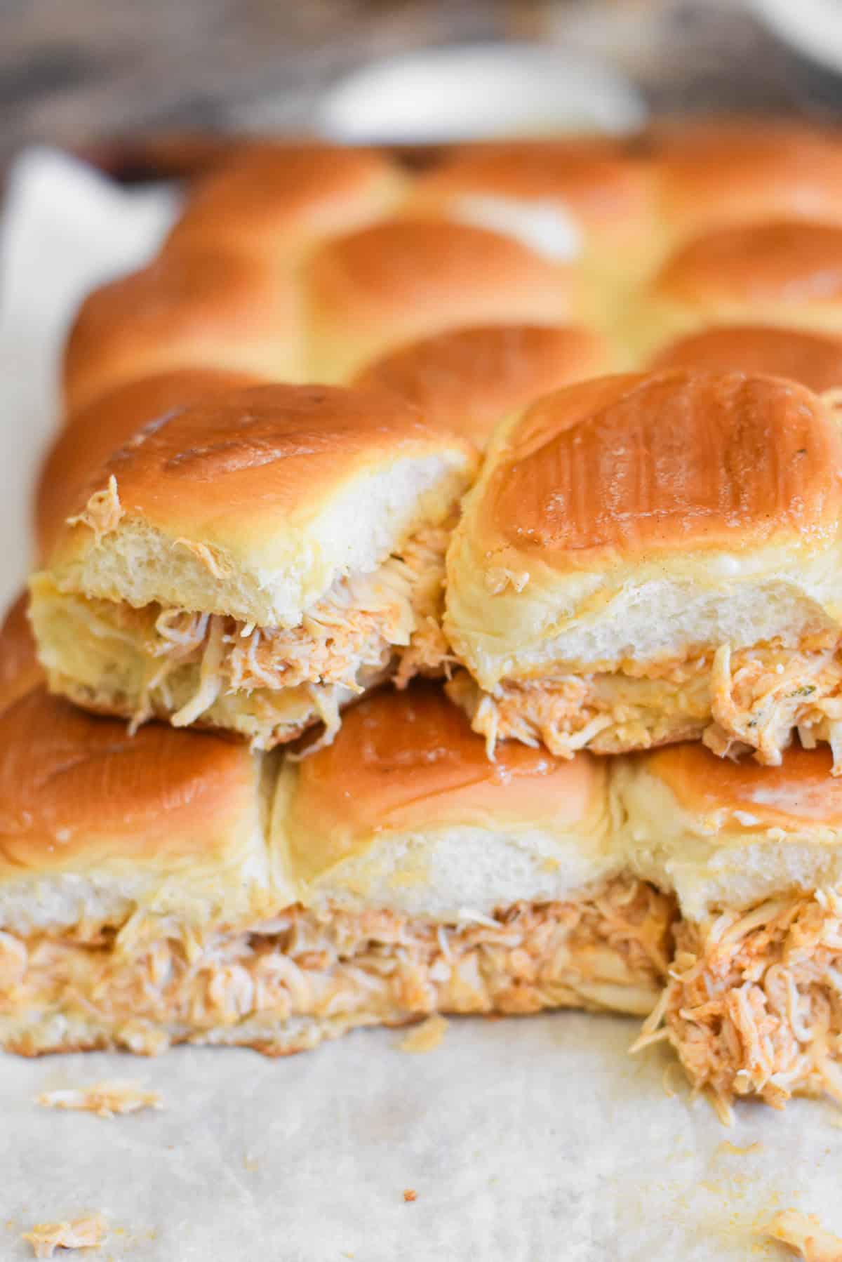 A stack of buffalo chicken sliders on a sheet pan.