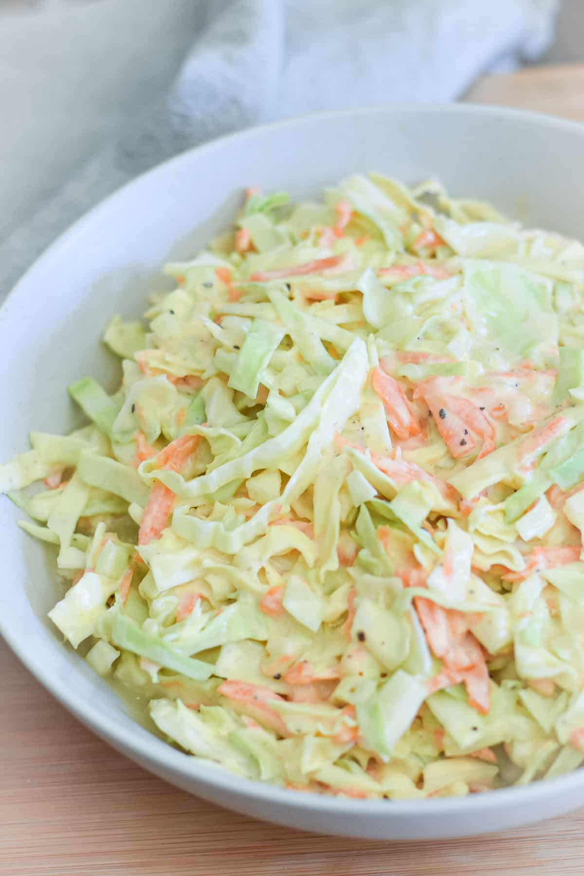 A bowl of American coleslaw with carrots and onion and a sweet dressing.