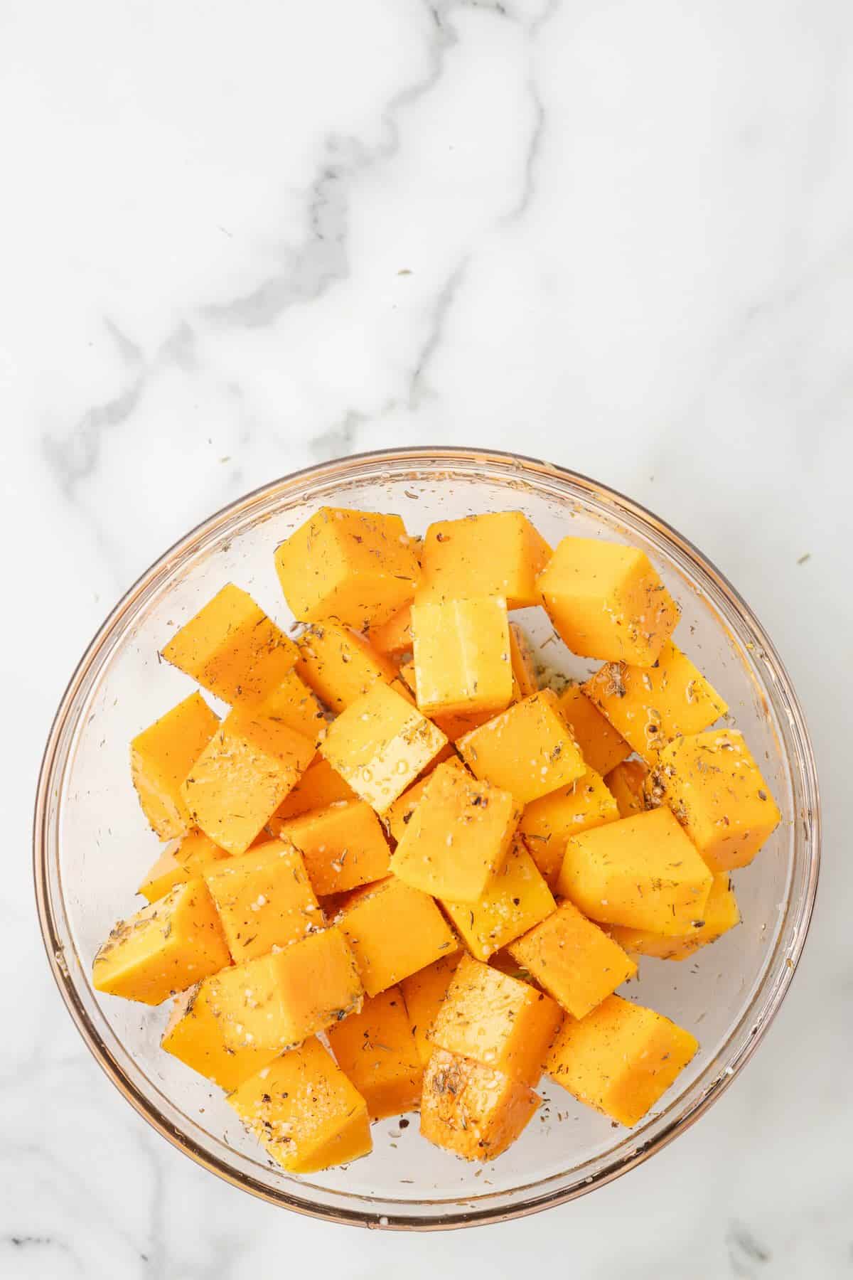 Seasoned butternut squash cubes in a bowl.