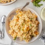 A bowl of butternut squash risotto topped with fresh chopped parsley.