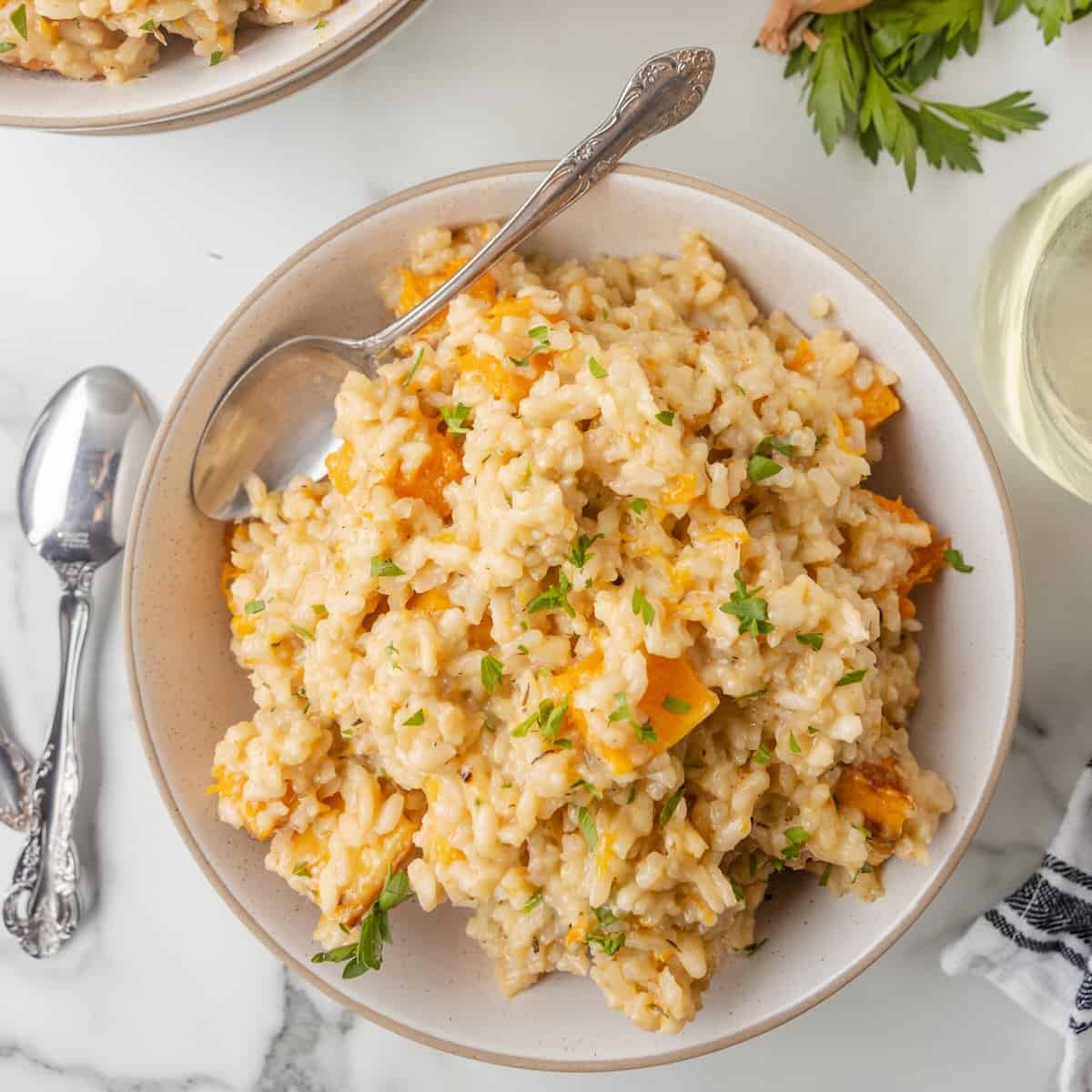 A bowl of butternut squash risotto topped with fresh chopped parsley.
