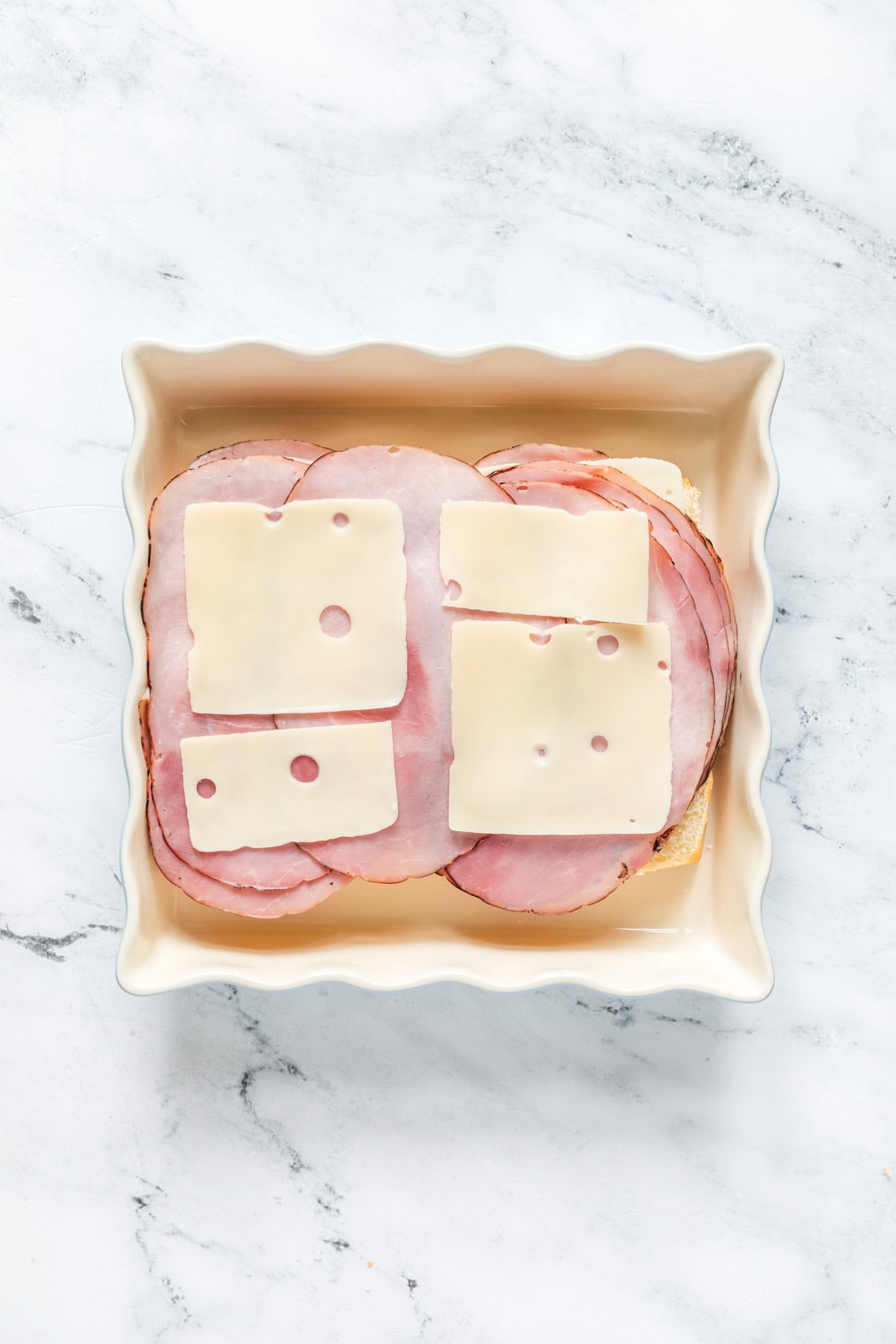 Laying ham and Swiss cheese on slider buns for funeral sandwiches.