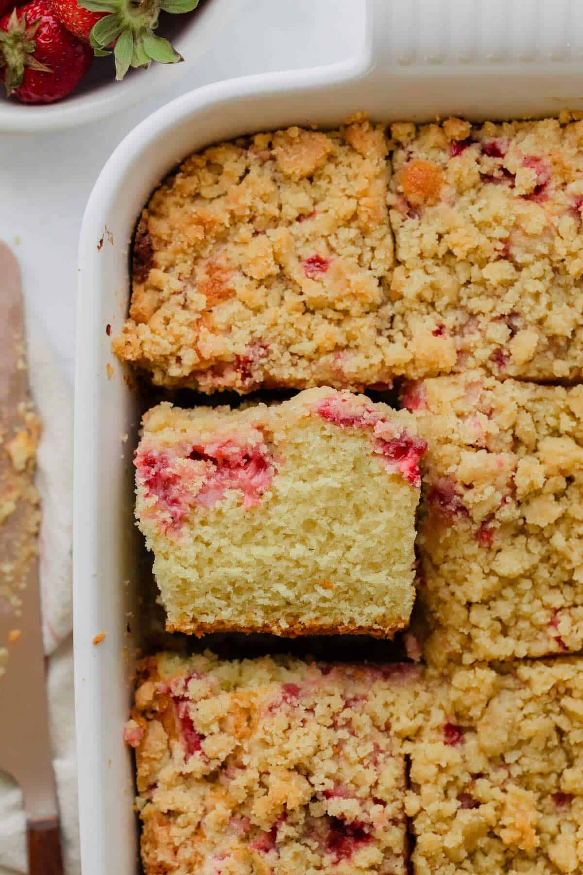 A piece of strawberry crumb cake cut from a dish.