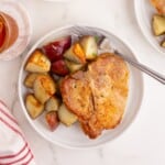 Bone in pork chops on a plate with seasoned potato pieces.