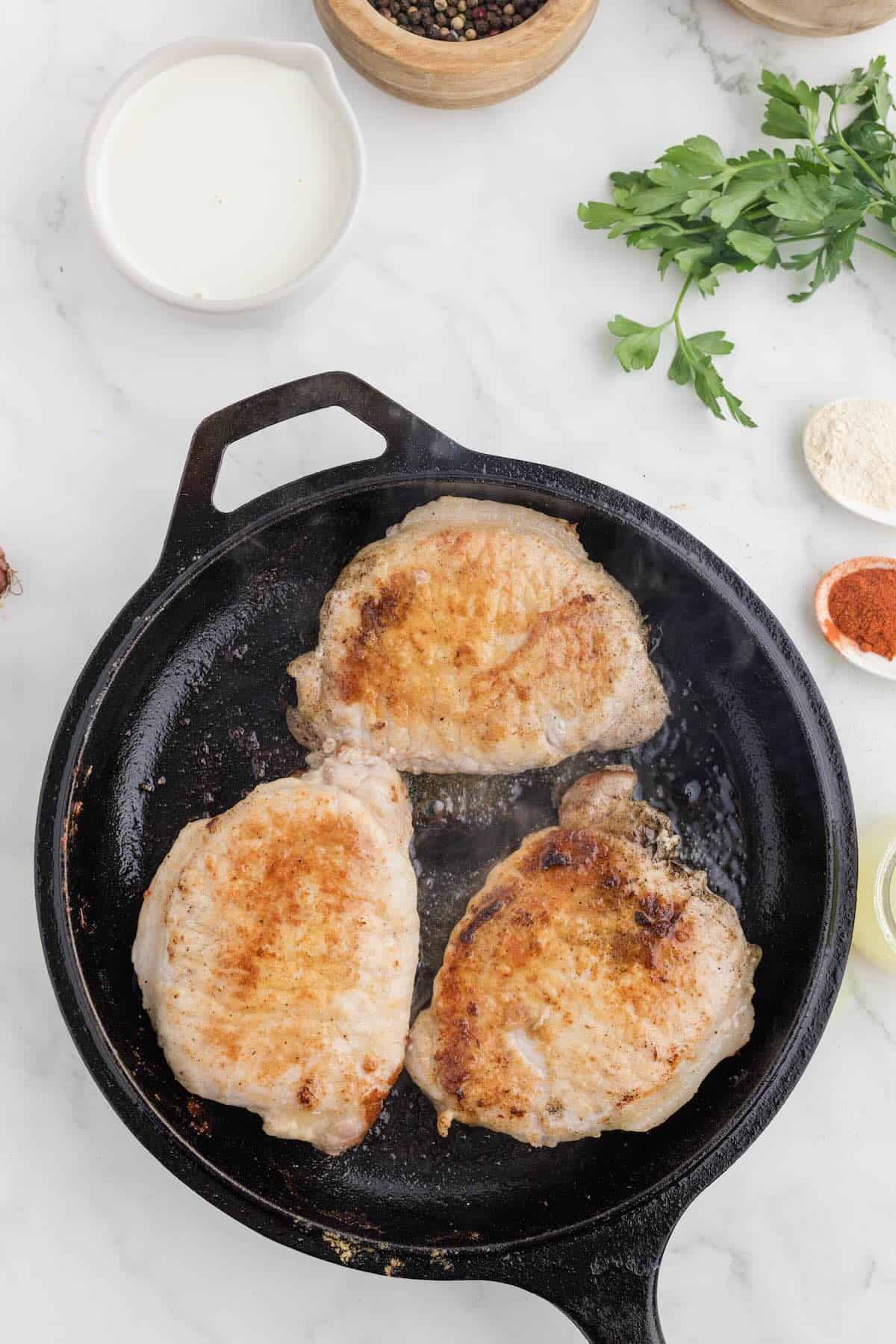 Browned pork chops in a cast iron skillet.