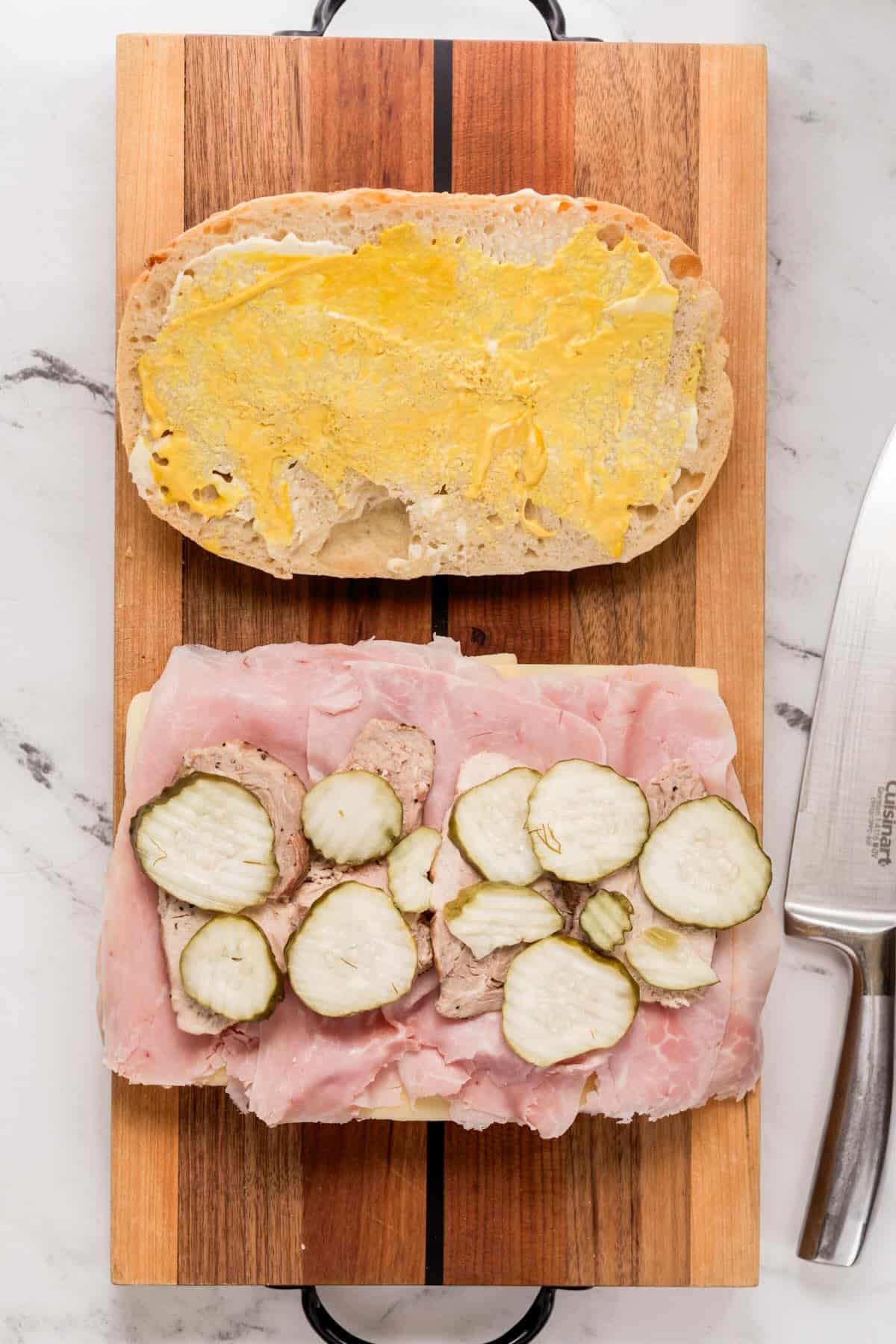 Mustard and mayo, ham and pickles layered on bread to make a Cuban sandwich.