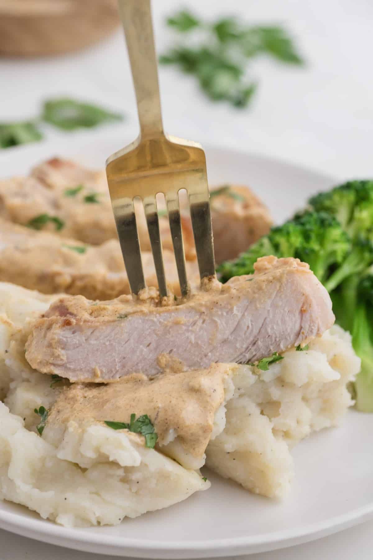 A bite of tender pork chop on a fork.