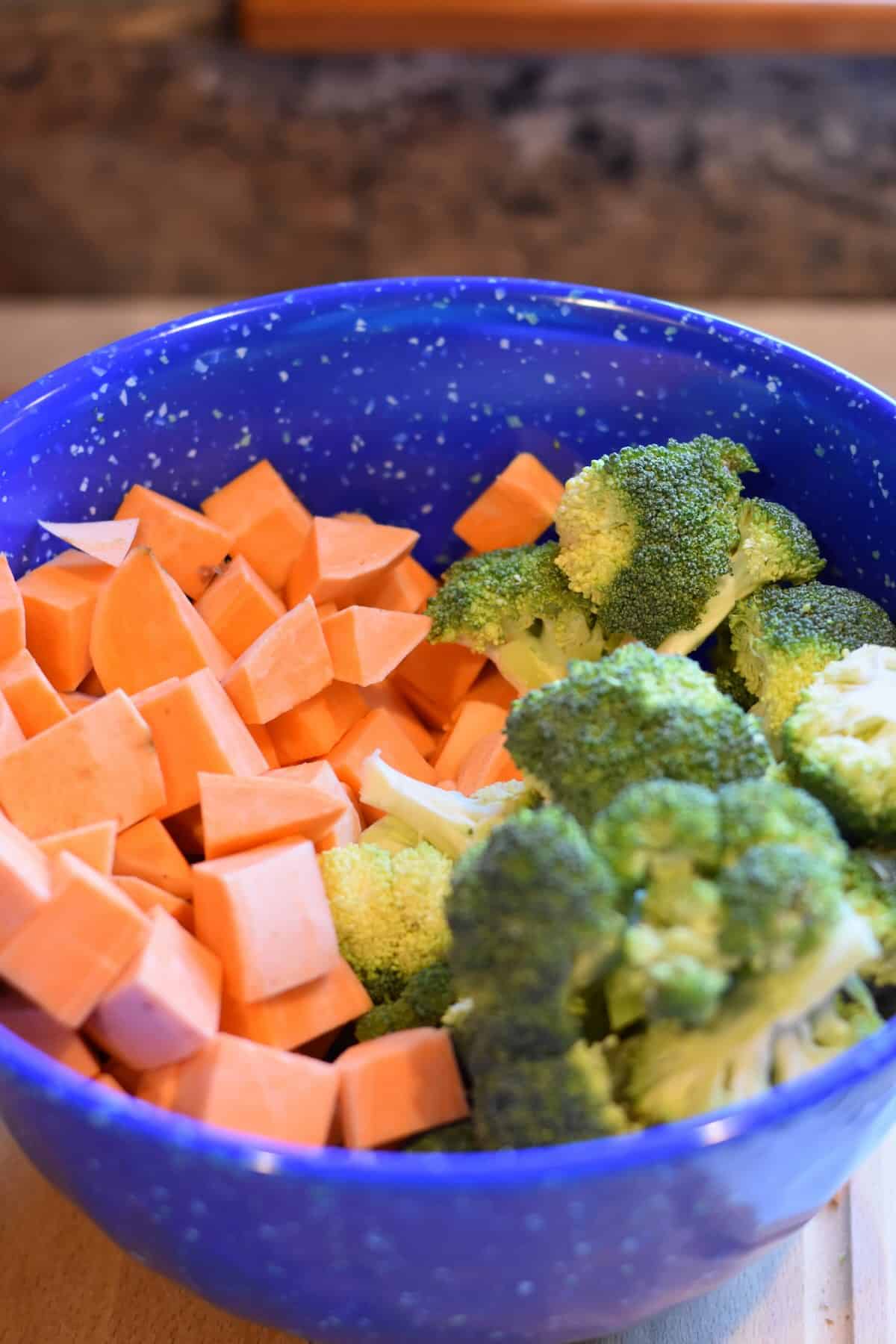 Chopped sweet potatoes and broccoli florets in a large bowl.