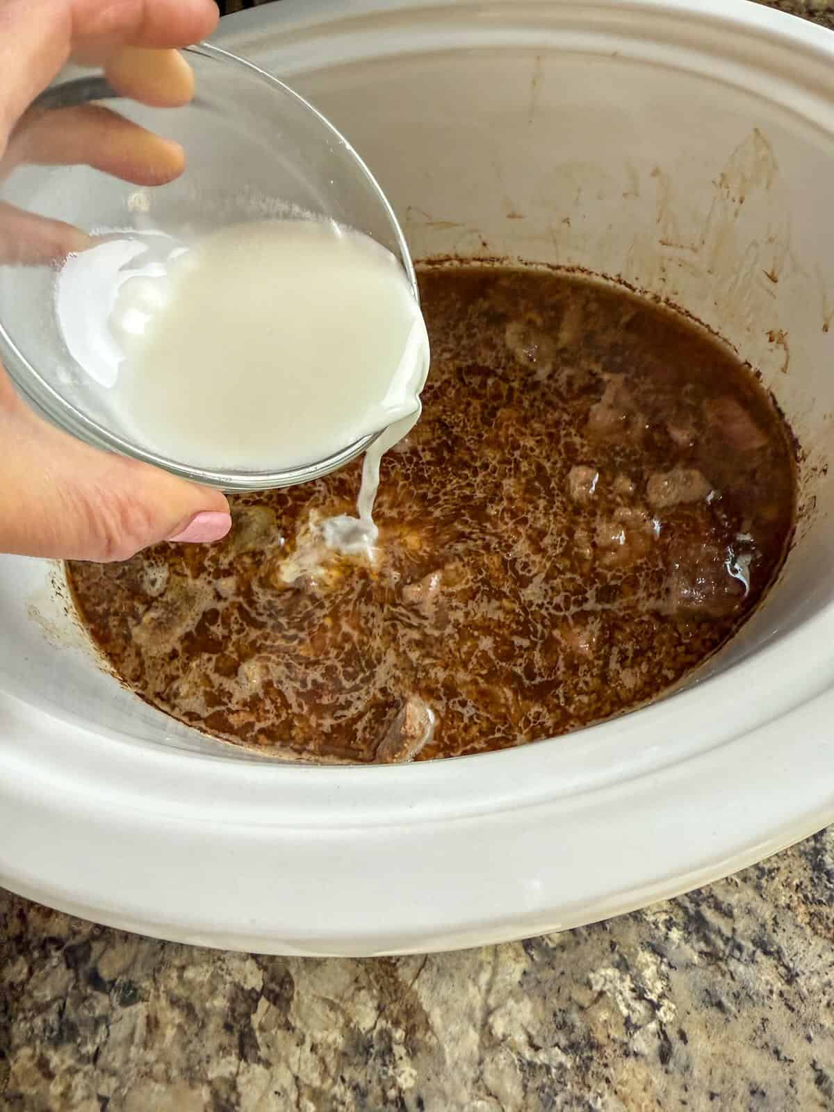 Close-up of glossy soy and sesame sauce coating beef and broccoli in crockpot