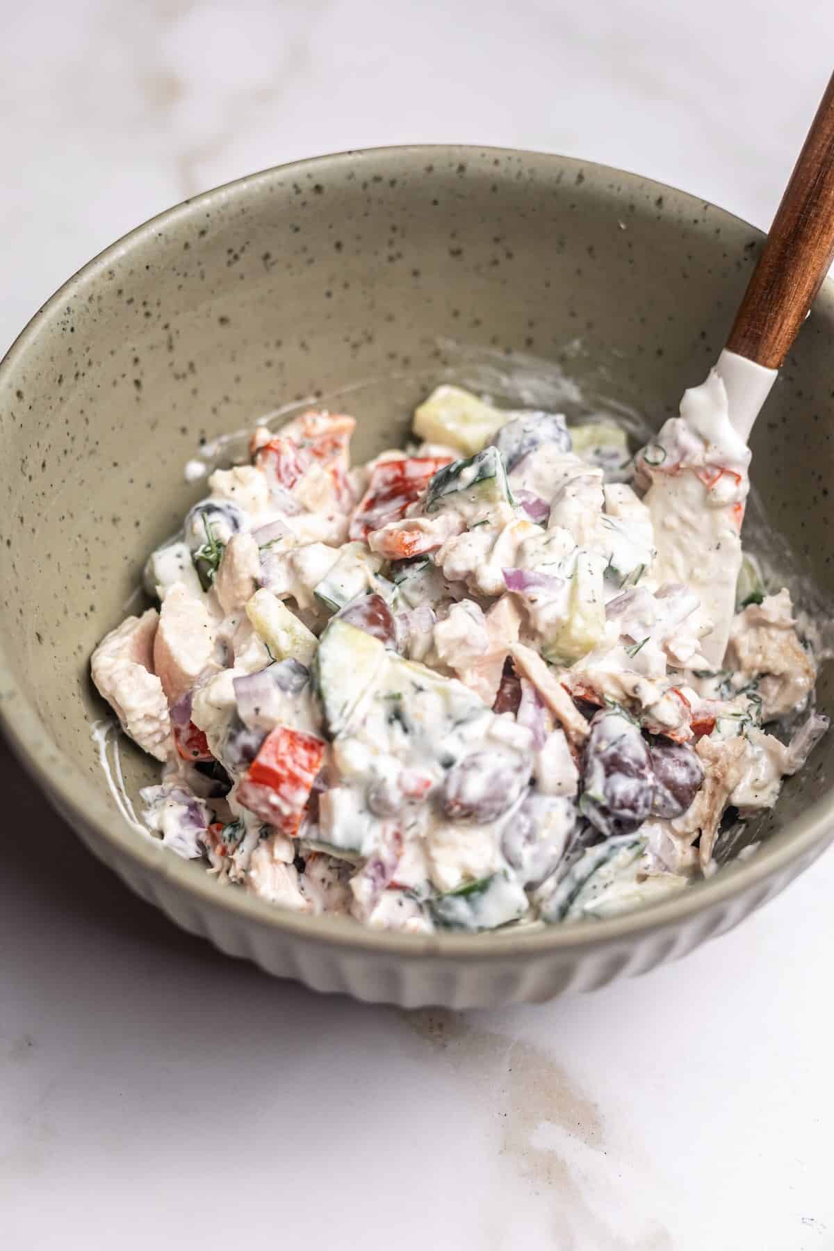 A close-up shot showing the creamy texture of Mediterranean tuna salad with chunks of tuna, crumbled feta and vegetables.