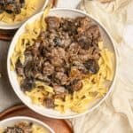 A bowl full of egg noodles topped with mushroom and beef stroganoff.