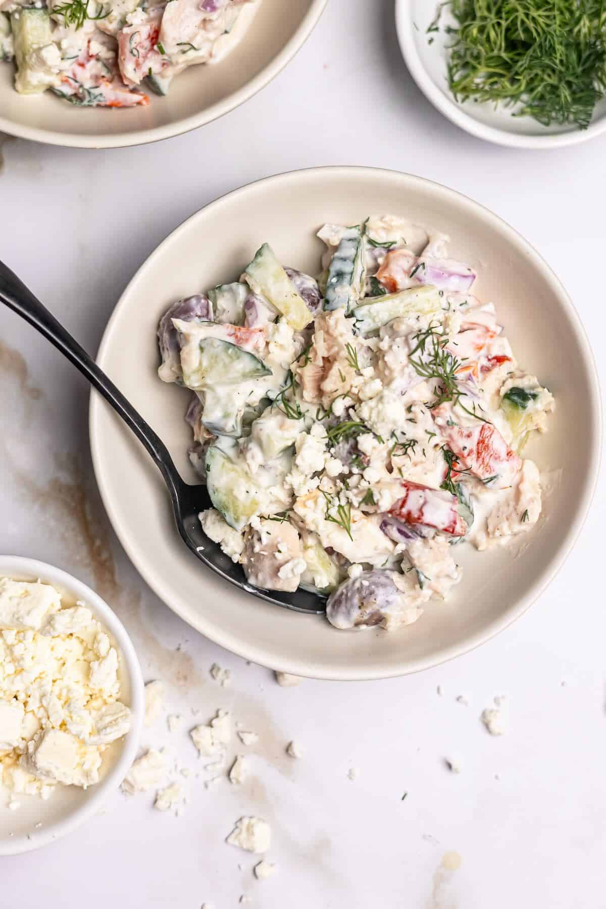 Mediterranean tuna salad in a bowl garnished with extra feta and dill.