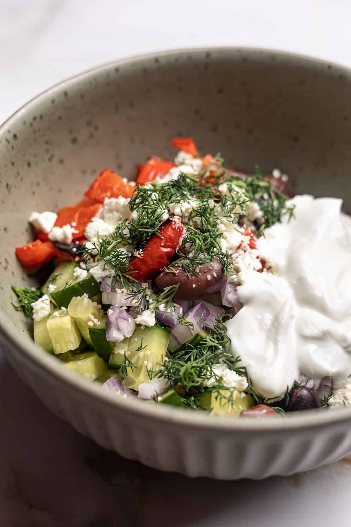 Greek yogurt, dill, cucumbers and tuna in a mixing bowl.