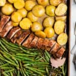 Flavorful pork tenderloin and roasted vegetables on a baking sheet, fresh out of the oven.