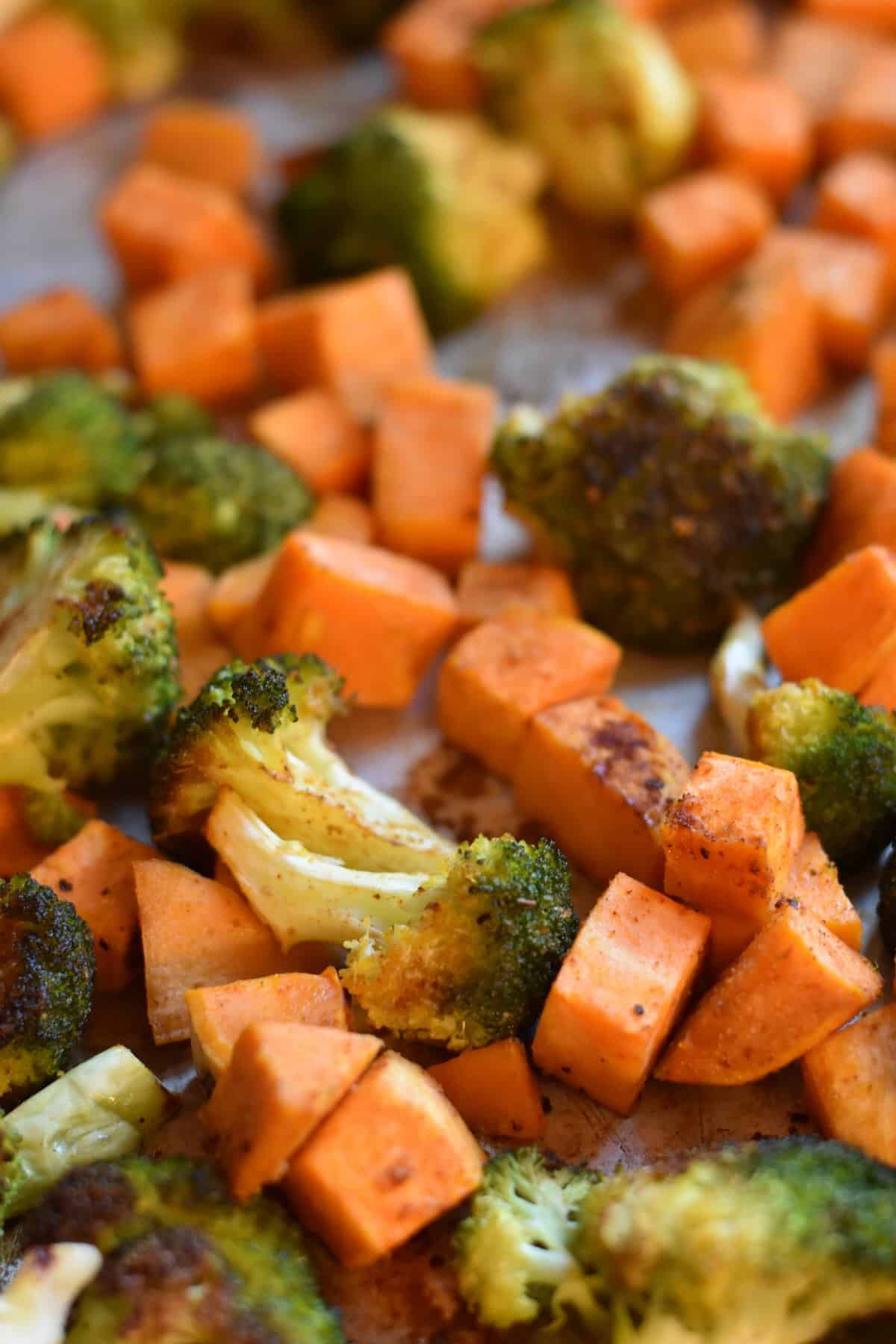 Cooked sweet potatoes and broccoli on a sheet pan.