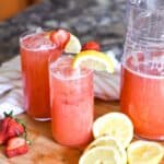 Glasses of strawberry lemonade topped with sliced fruit.