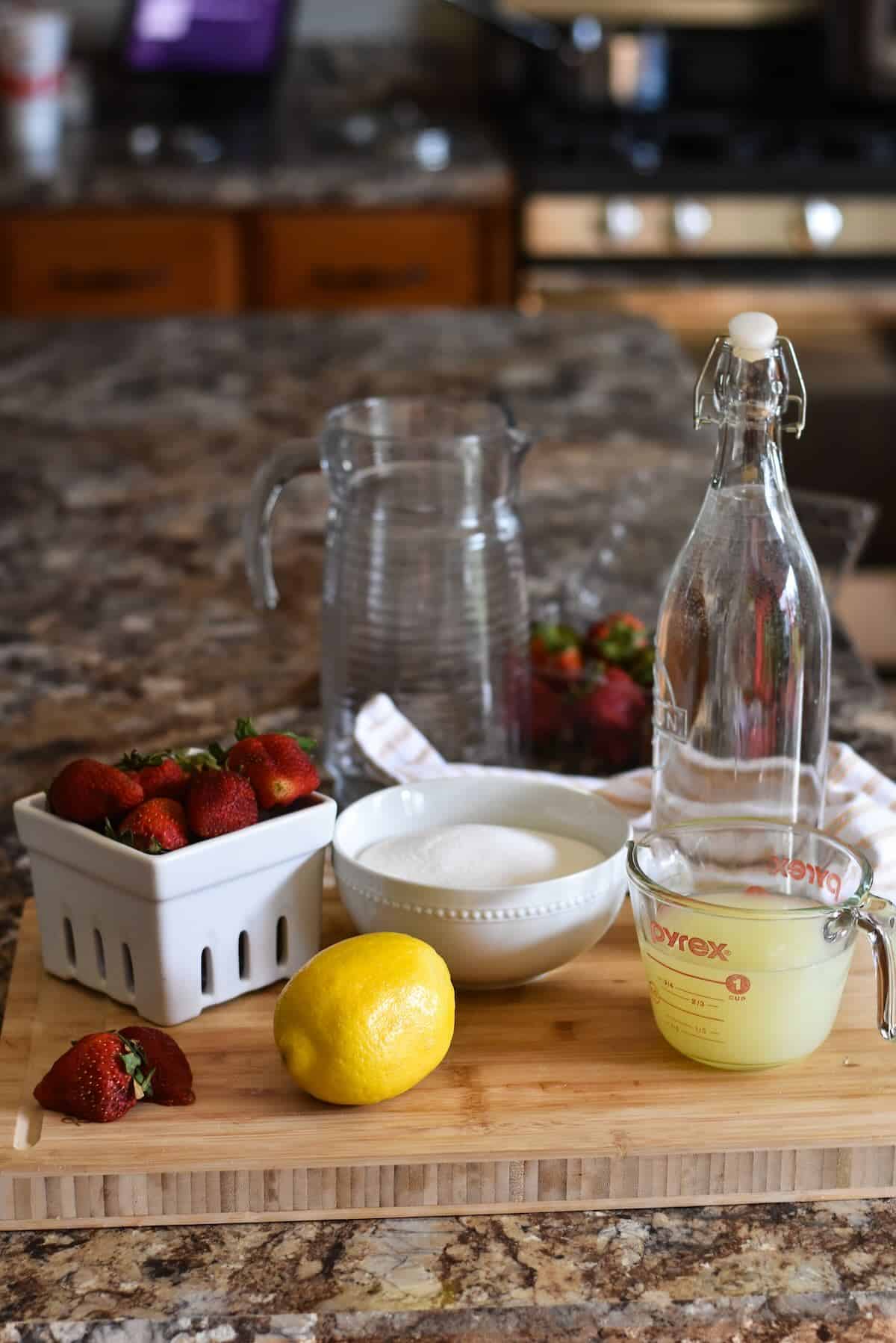 Simple ingredients including strawberries and lemons to make a beverage.