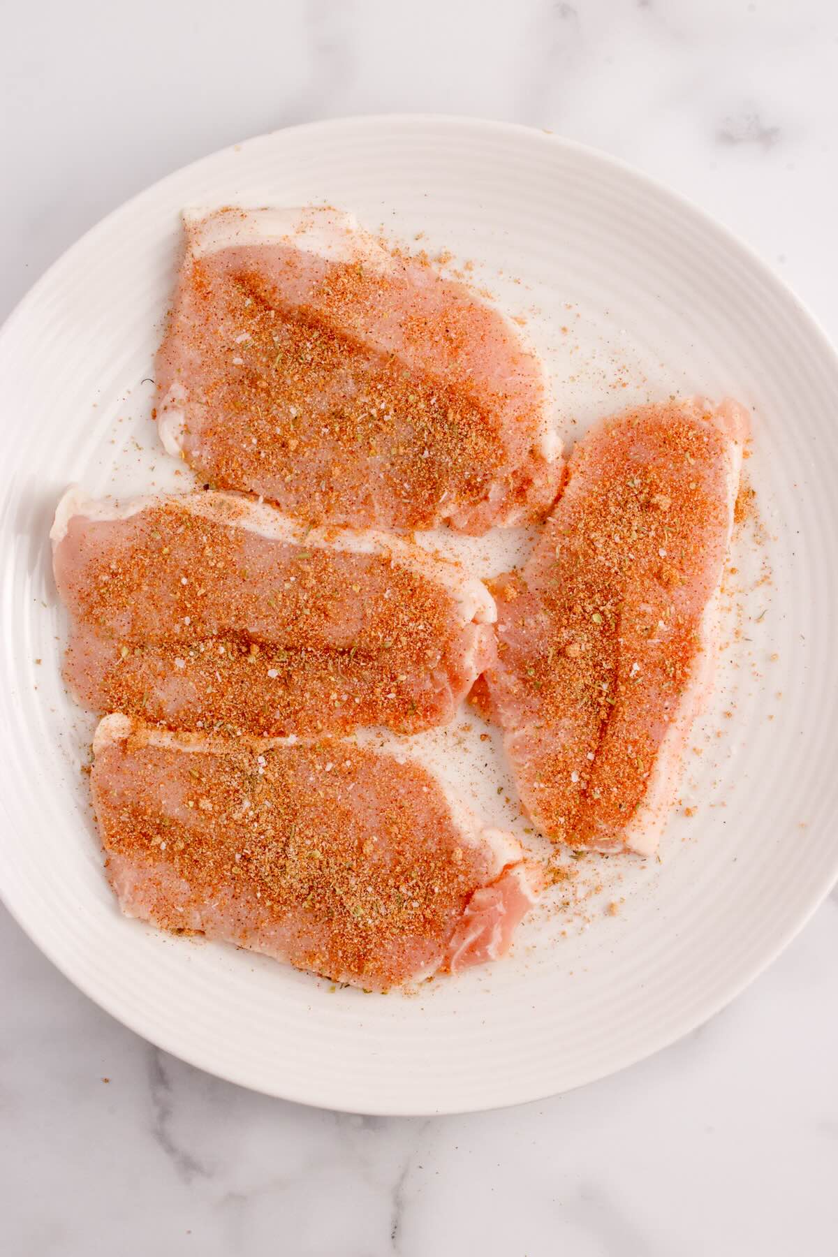 Thinly sliced seasoned pork chops on a plate.