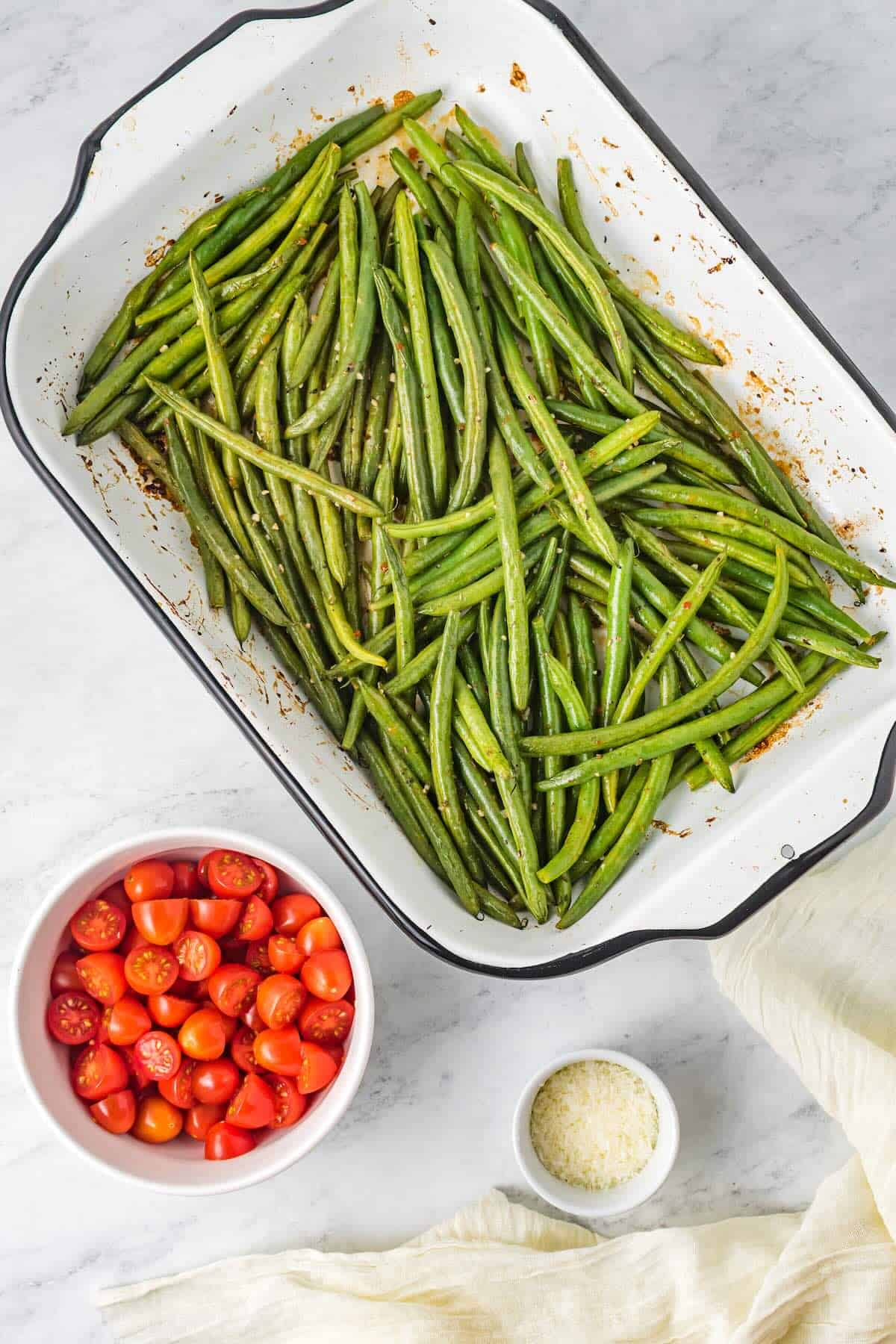Green beans tossed with Italian dressing in a casserole dish, ready to be baked.