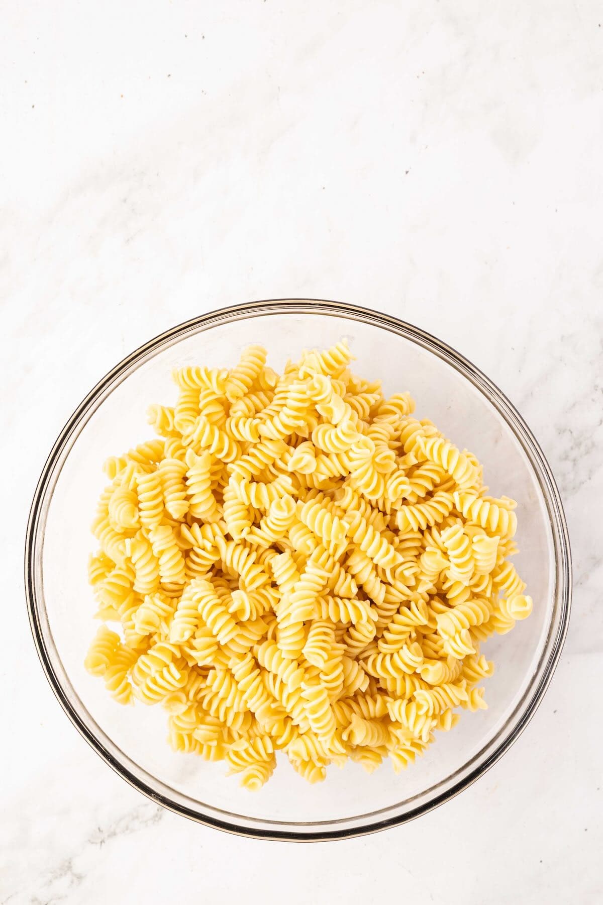 Cooked rotini pasta in a glass bowl.