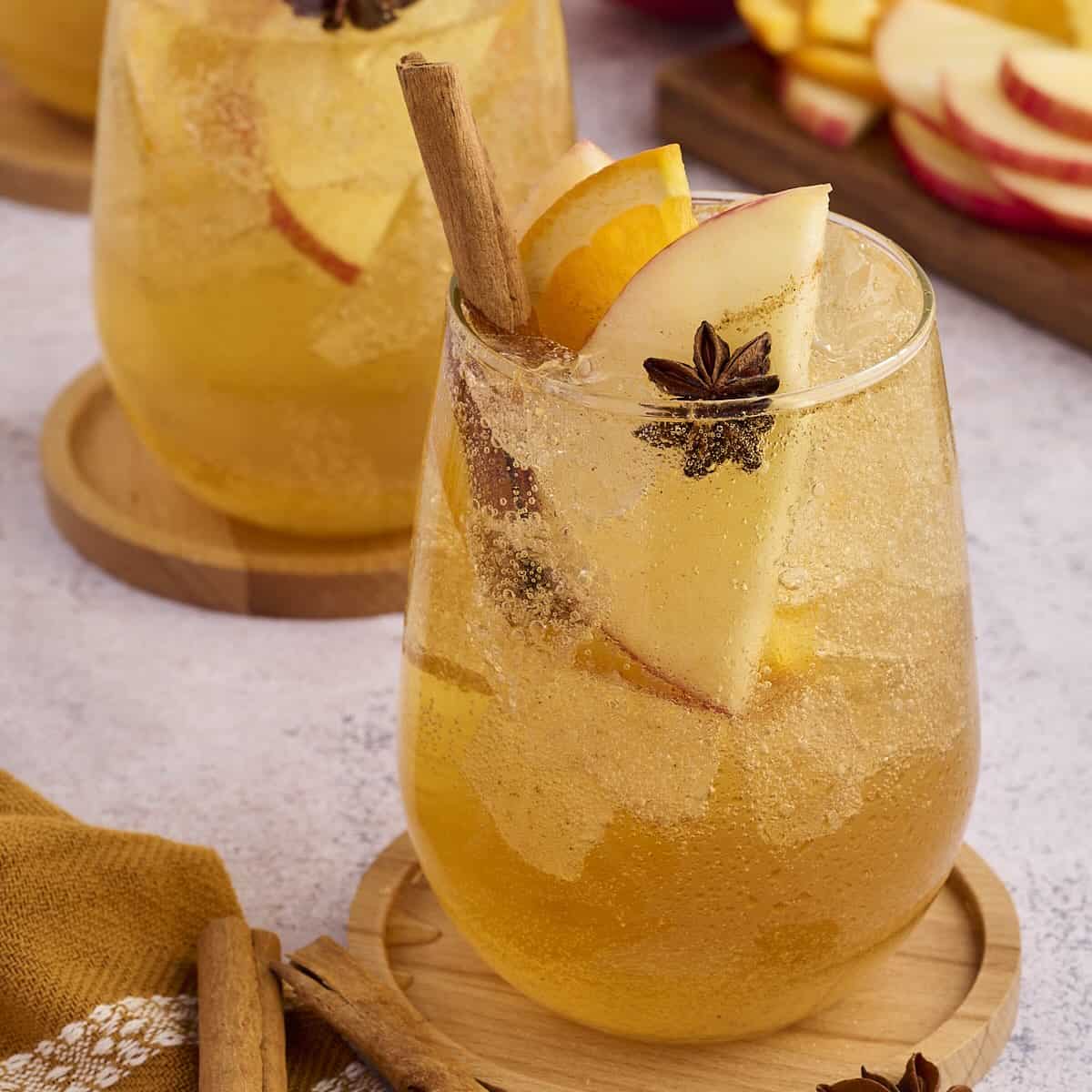 Glass of apple cider punch garnished with fresh apple slices and a cinnamon stick.