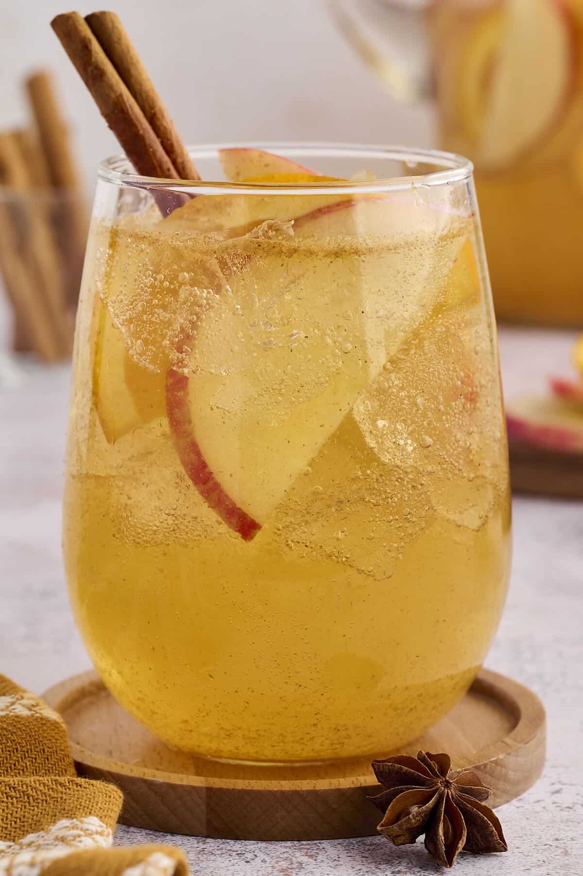 Glass of homemade apple cider punch with sliced apples and oranges.