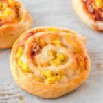 Close-up of freshly baked breakfast pinwheels with scrambled eggs, salsa and cheese.