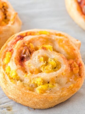Close-up of freshly baked breakfast pinwheels with scrambled eggs, salsa and cheese.